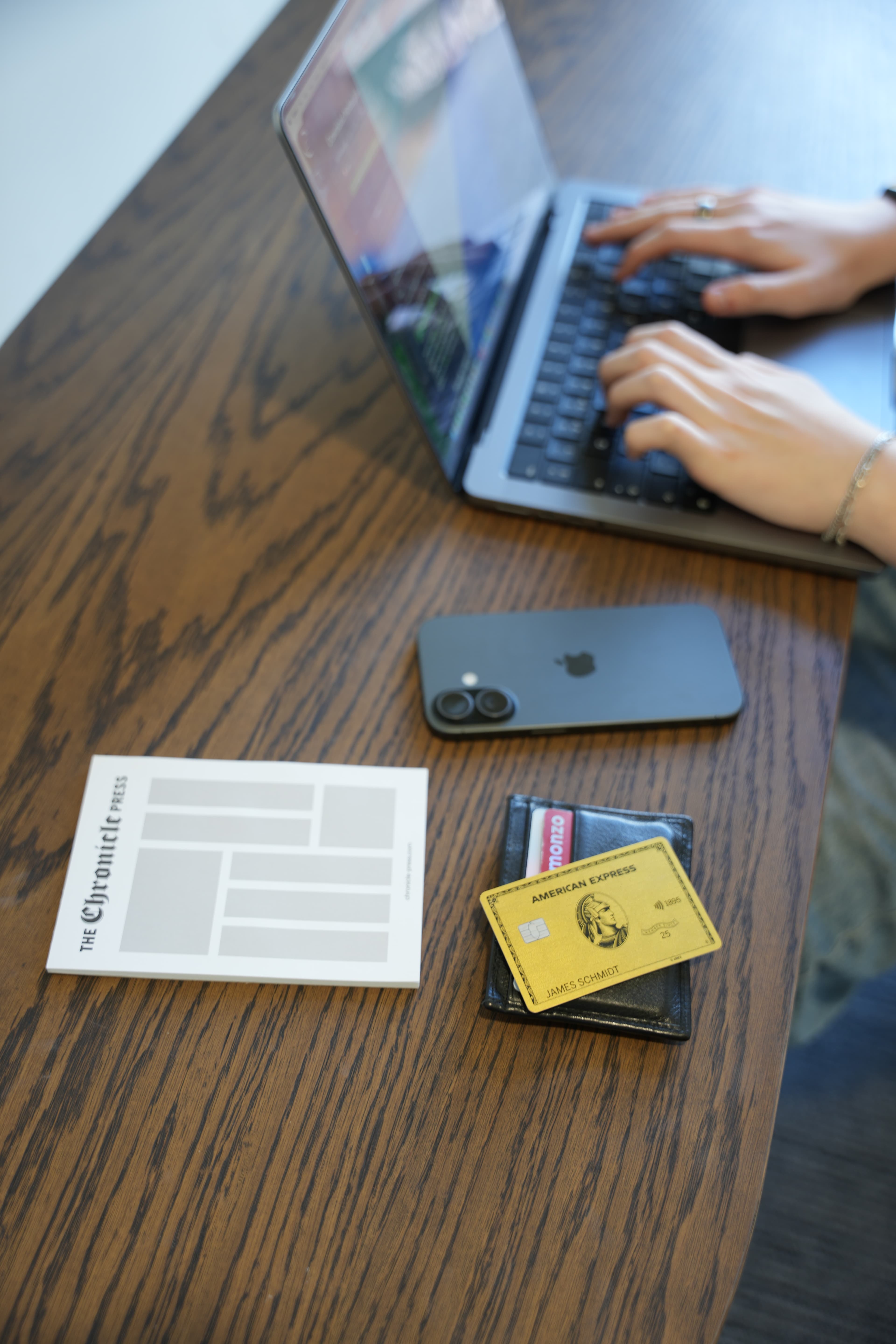 Amex Gold card, Monzo card, iPhone and laptop on desk